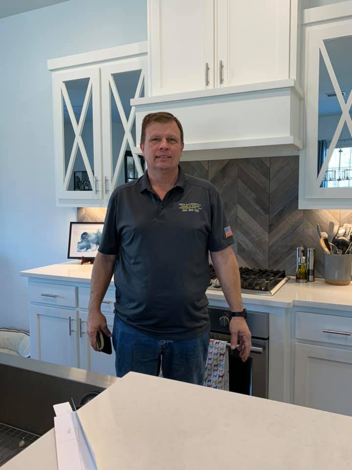 A man standing in a kitchen next to a counter