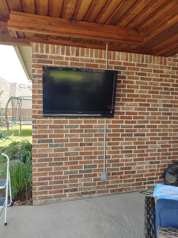 A flat screen tv mounted to a brick wall